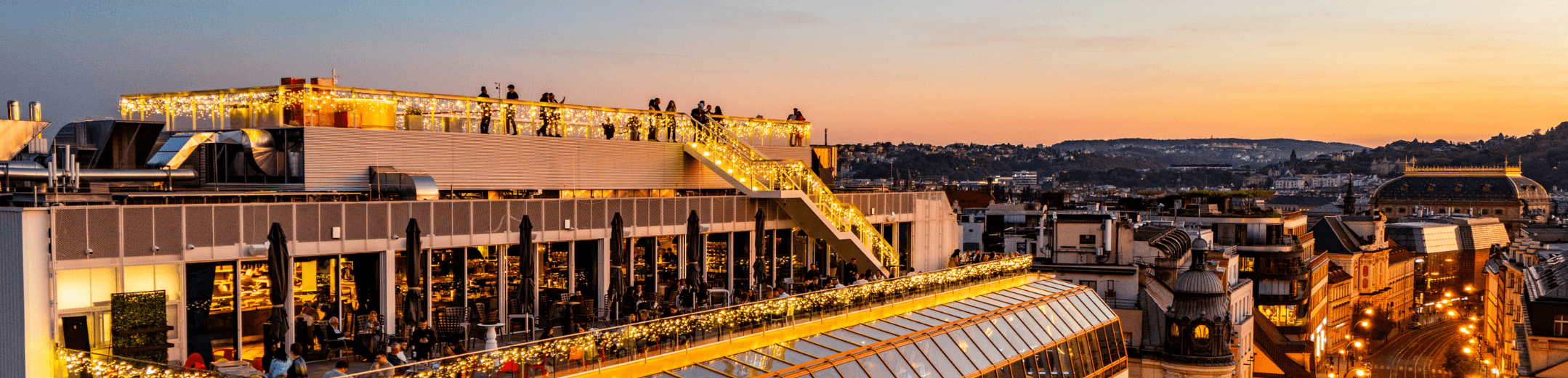 Fotka střešní terasy na obchodním domě MÁJ při západu slunce.